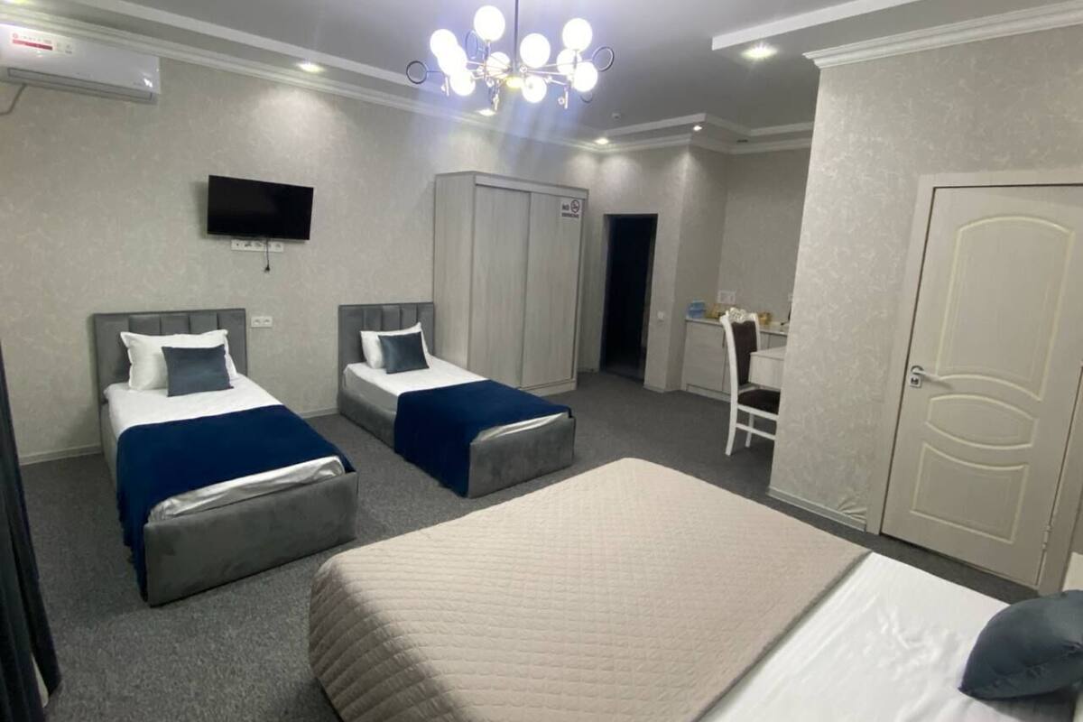A hotel room with two beds, a television, a wardrobe, and a desk with a chair.