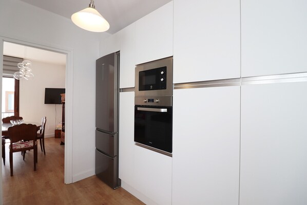 A modern kitchen with white cabinetry, a stainless steel refrigerator, a microwave, and an oven. - 1032 Casa Victoria (Nerja)