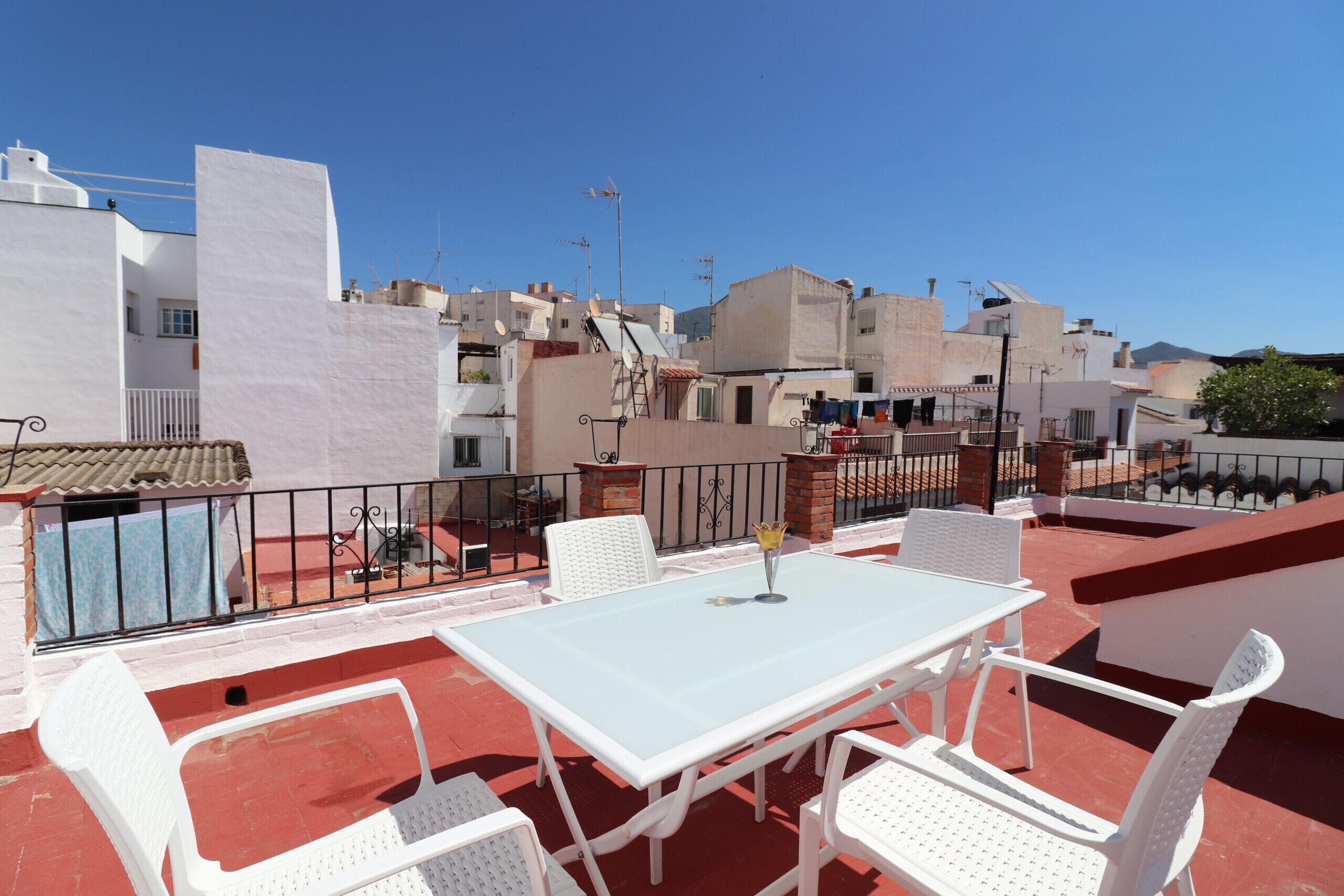 Eine Dachterrasse mit Tisch und Stühlen, Blick auf die Stadt und einem strahlend blauen Himmel.