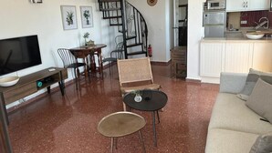 Un salon comprenant un téléviseur, un canapé, une table à manger, des chaises et un escalier en colimaçon.