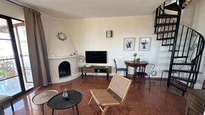 Un salon spacieux doté d’une cheminée, d’un téléviseur et d’un escalier en colimaçon.