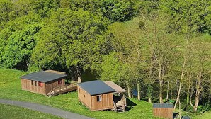 A rustic cabin with a wooden exterior, a small shed, and a covered area with a staircase leading to a deck.