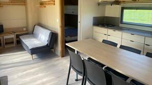 A compact, modern RV interior with a kitchenette, a dining area, a seating area, and a sleeping space.