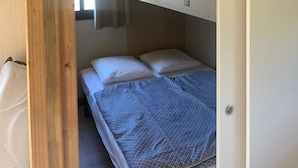 A bunk bed with a hanging light fixture, a window with curtains, and a door.