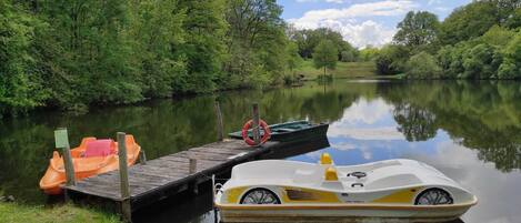 Une rivière paisible avec un quai en bois, un petit bateau et une barque à rames.