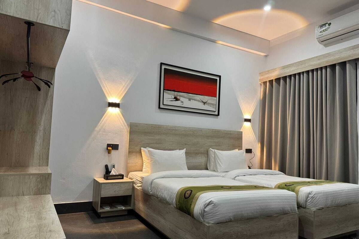 Habitación de hotel moderna con una cama grande, mesitas de noche, aire acondicionado montado en la pared y un cuadro.