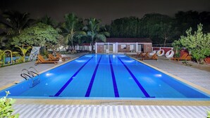 A swimming pool with a clear blue waterline, surrounded by lounge chairs and palm trees. - Kokomo Sunset Resort (Sreepur)