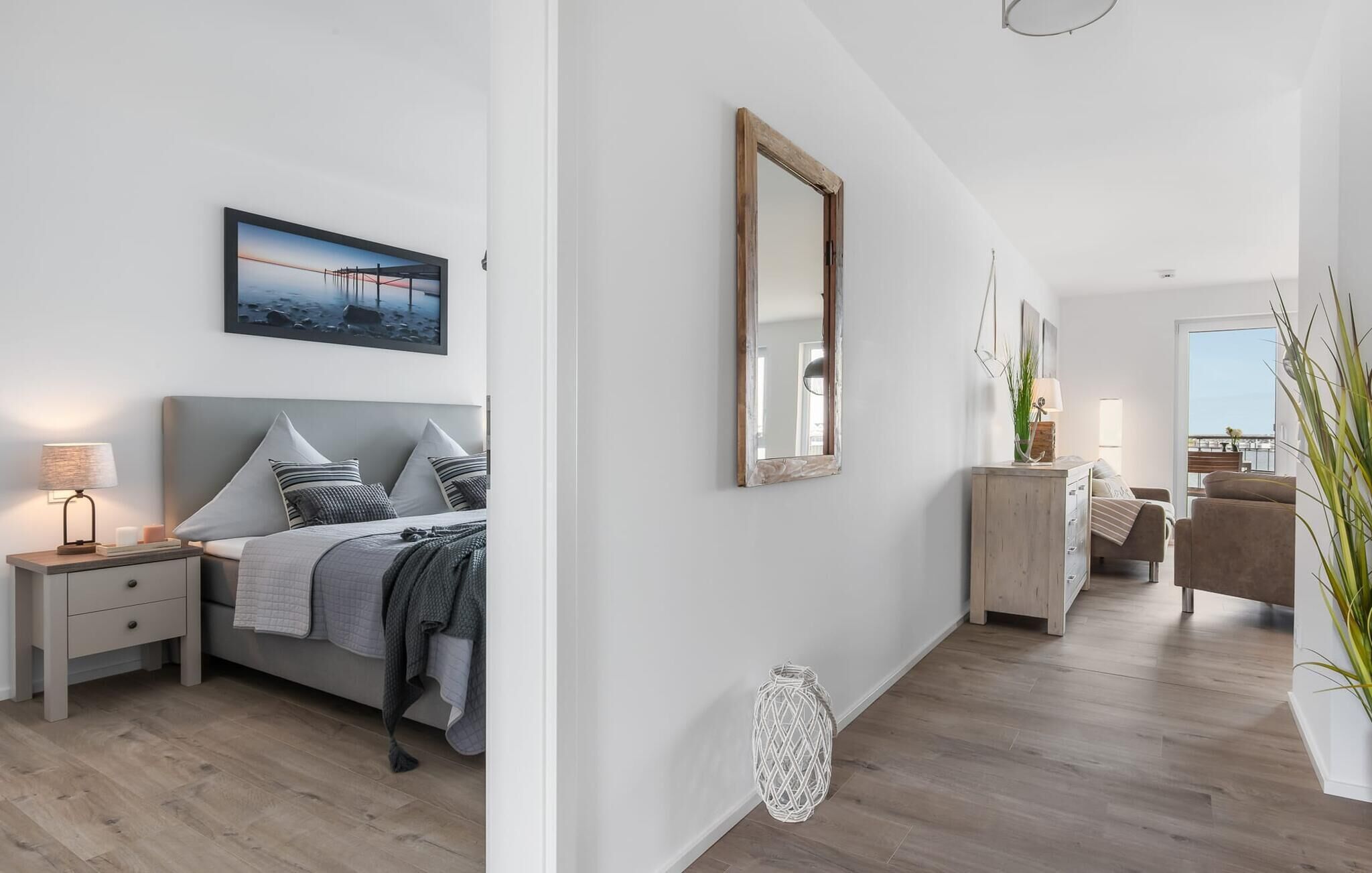 A modern bedroom with a bed, bedside table, and a large mirror.