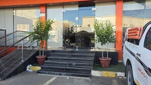 A building with a sign for serviced apartments, a staircase, and a parked vehicle. - Wadan Al-Mutamayeza Furnished Apartments (Rabigh)