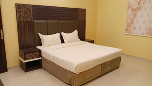 A bedroom with a large bed, two bedside tables, and a headboard with a geometric pattern. - Wadan Al-Mutamayeza Furnished Apartments (Rabigh)