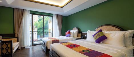 A hotel room with two beds, a wooden floor, a balcony with curtains, and a green wall.