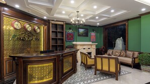 Un vestíbulo con mostrador de recepción, chimenea, sofá y candelabro.