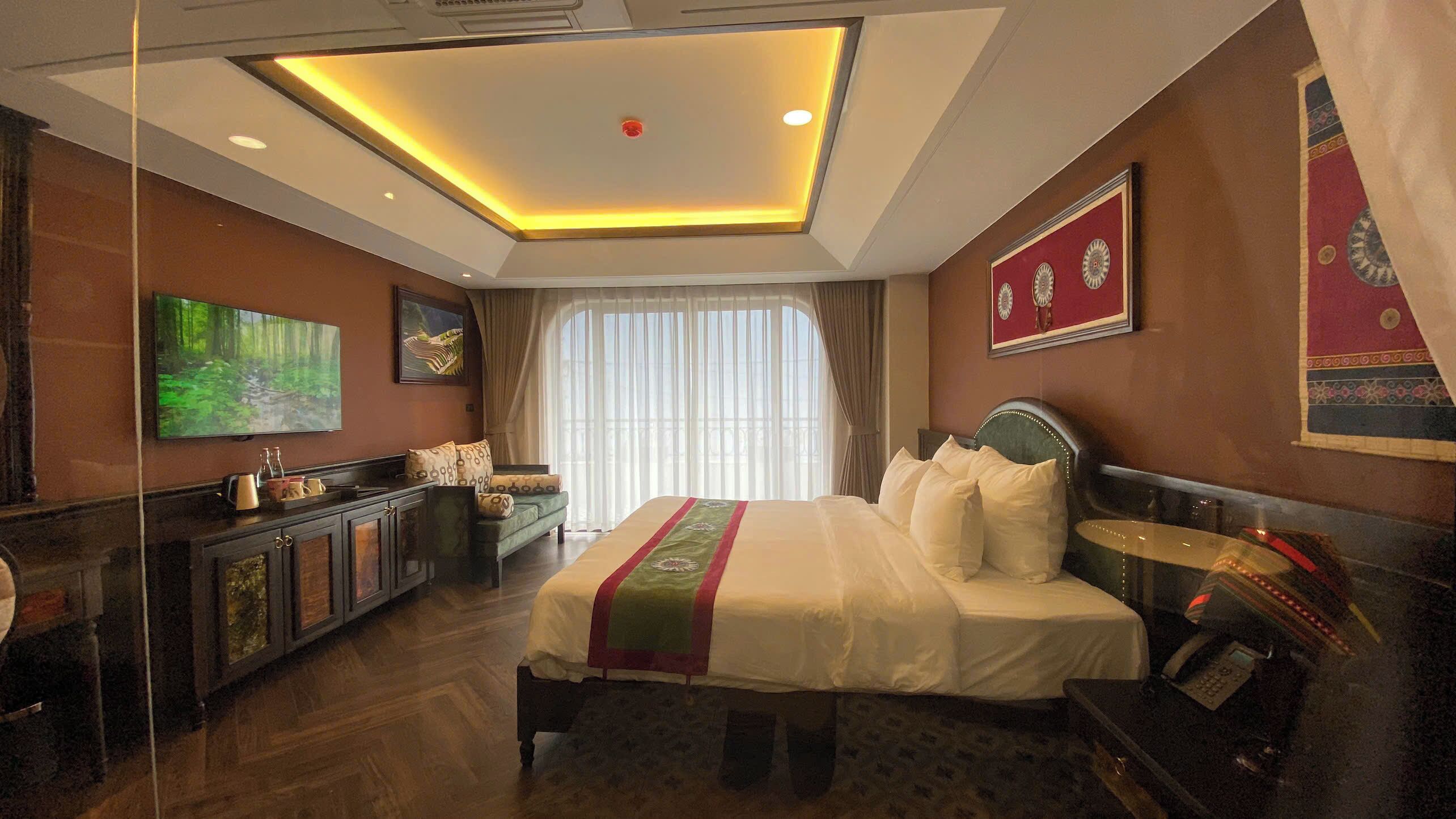 Une chambre d’hôtel avec un grand lit, une télévision, un bureau et une vue sur l’extérieur.