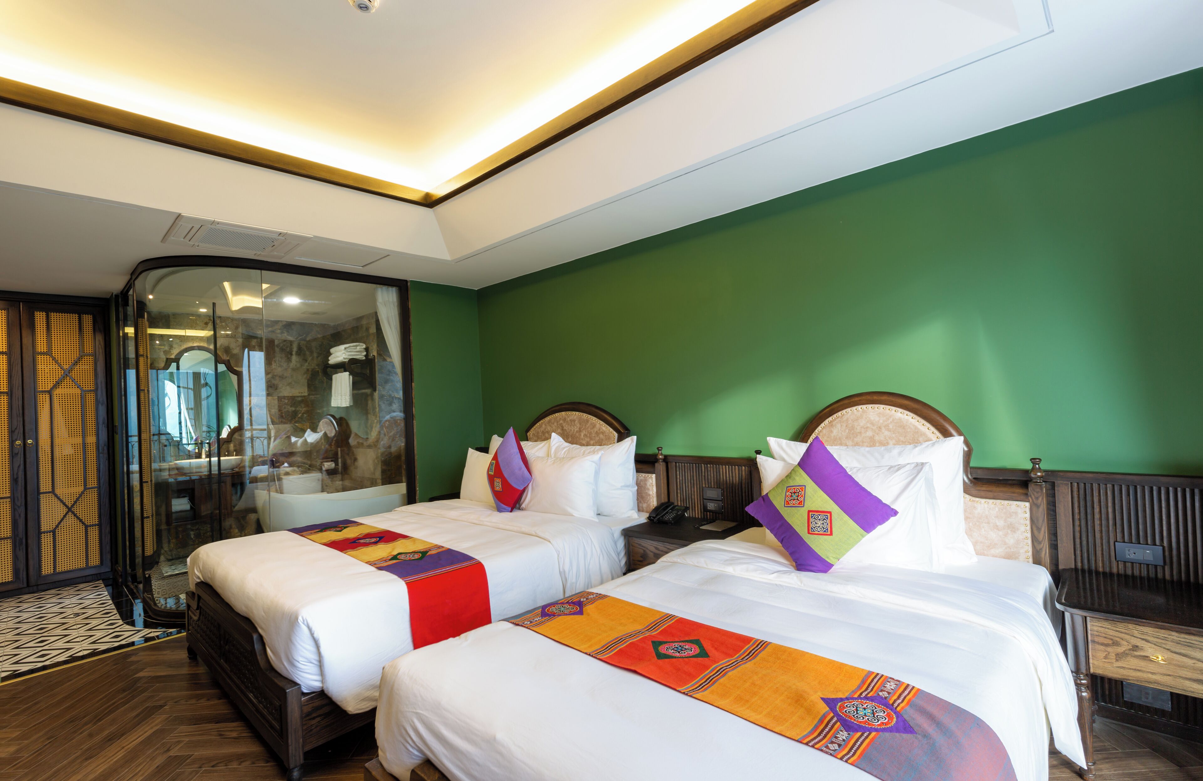 Habitación de hotel con dos camas, cabina de ducha de vidrio y una pared verde.