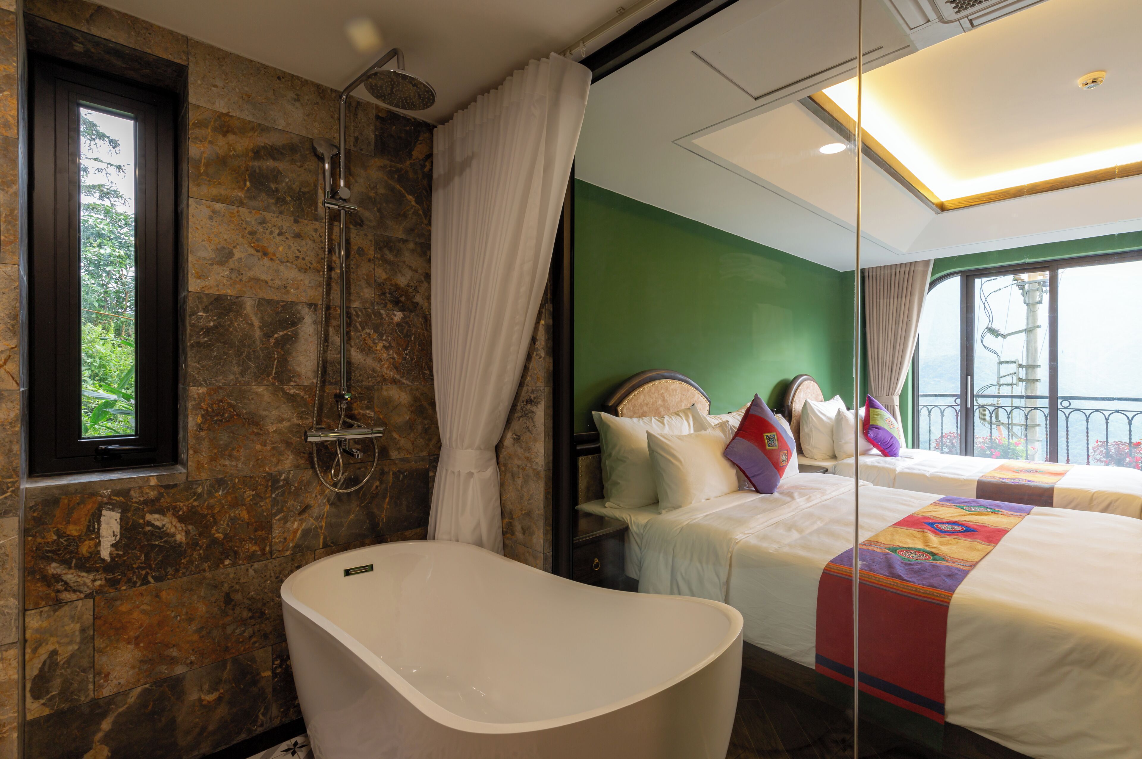 Un baño con una bañera independiente, ducha y ventana con cortinas.
