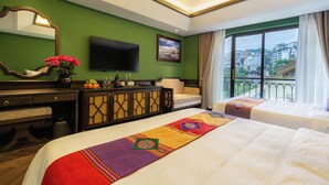Habitación de hotel con dos camas, televisor, ventana grande con vistas a la ciudad, pared verde y una alfombra decorativa.