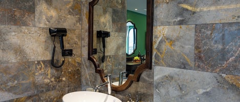 A bathroom with a large oval sink, a mirror, and a hairdryer mounted on the wall.