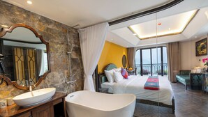 Habitación de hotel moderna con una bañera grande, zona de ducha separada, una cama amplia y un balcón con vistas.