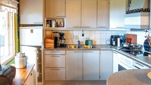 Una cocina con armarios de madera, una estufa y diversos electrodomésticos.