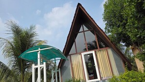 A small, triangular-roofed building with a covered outdoor seating area and a door leading inside. - PATANG FAMILY RESORT (Talala)
