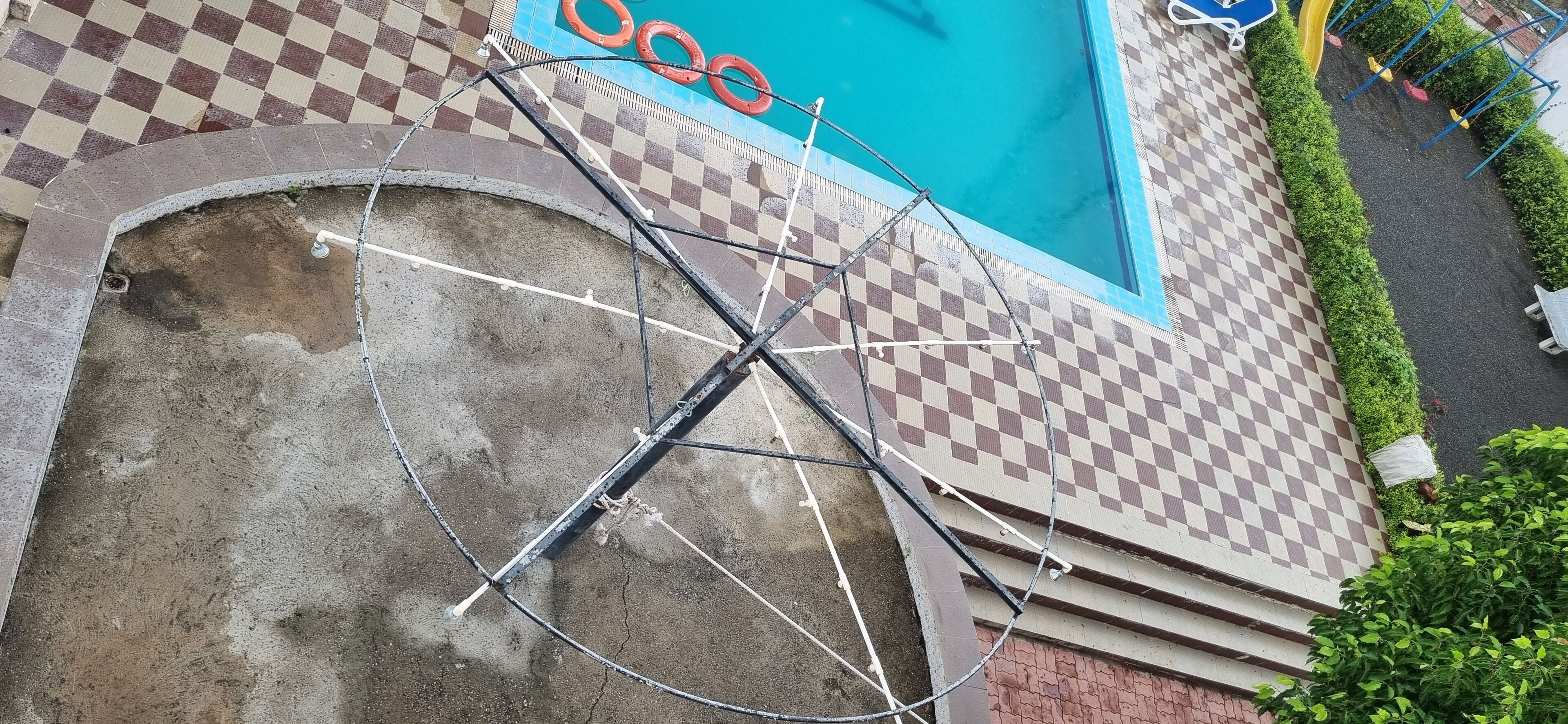 A pool area with a checkered floor, a bicycle leaning against a wall, and a blue pool.