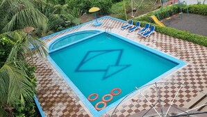 A swimming pool with a checkered deck, lounge chairs, and a slide. - PATANG FAMILY RESORT (Talala)