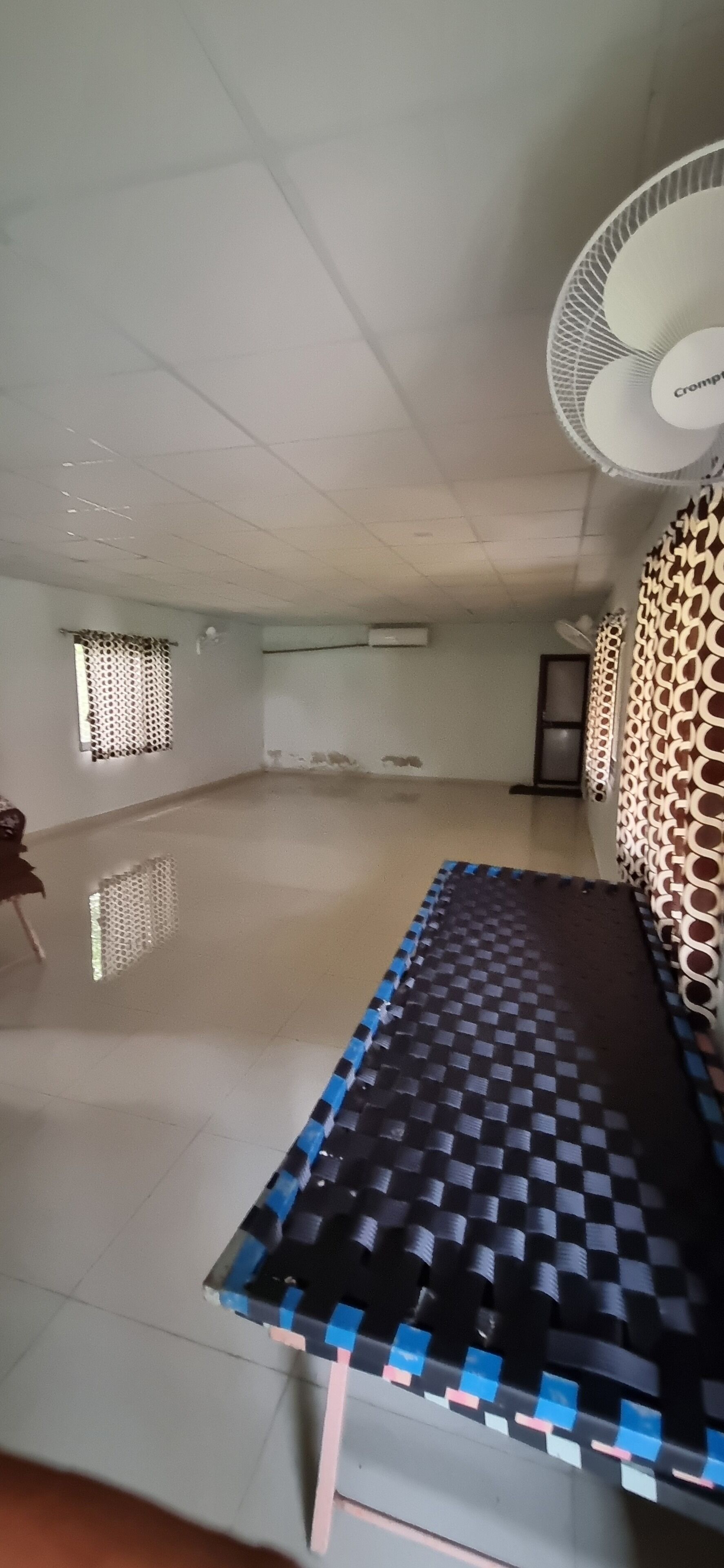 A spacious room with a large checkered mat, a ceiling fan, and a patterned wall.