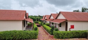 Reihenweise Bungalows mit roten Ziegeldächern und einem gepflasterten Weg, der durch ordentlich geschnittene Hecken führt.