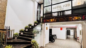 Entrada de hotel con una escalera que conduce al piso superior, un felpudo y un letrero con el número del hotel.