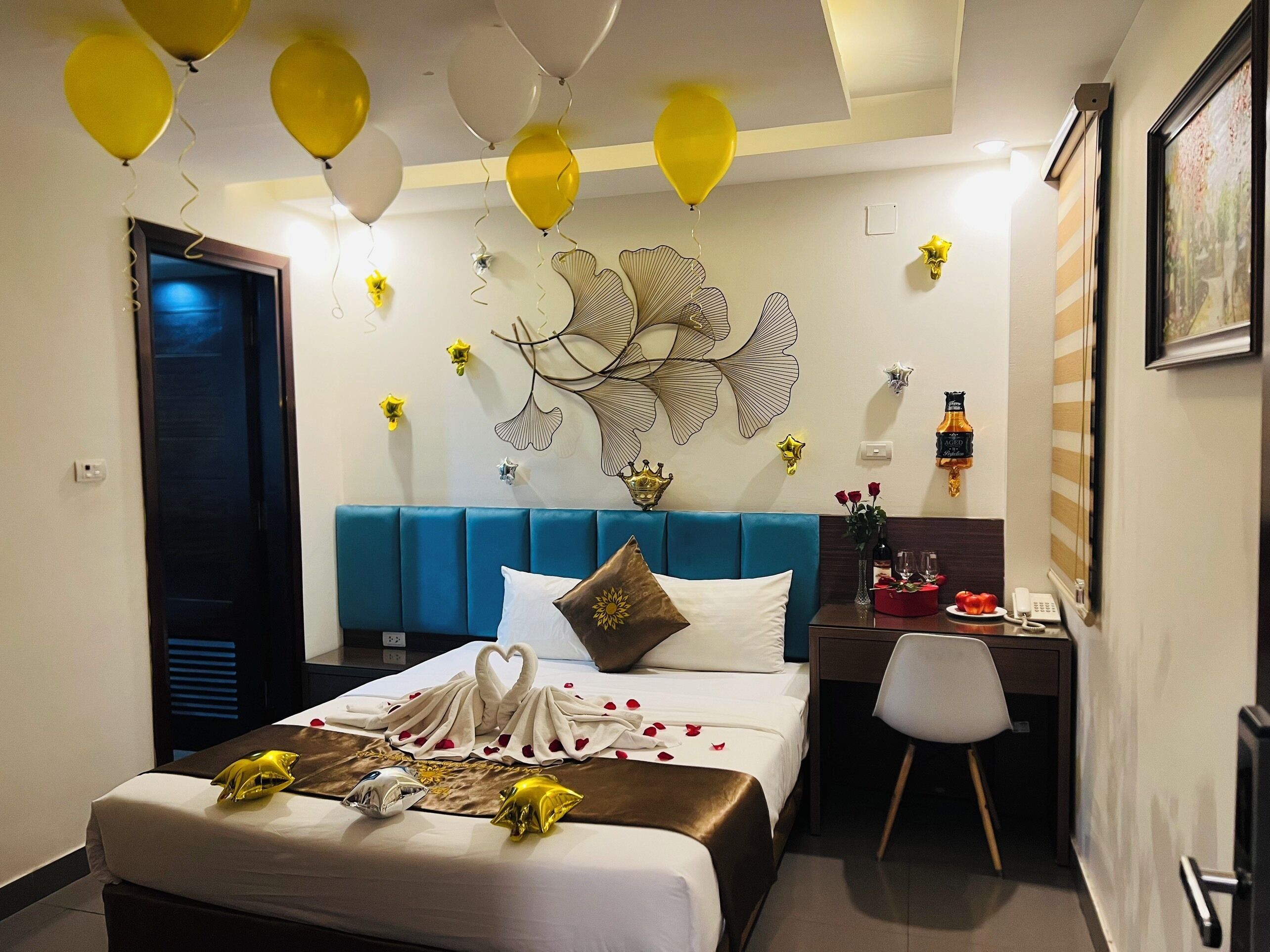 Habitación de hotel con cama, escritorio y silla. Hay globos en el techo.