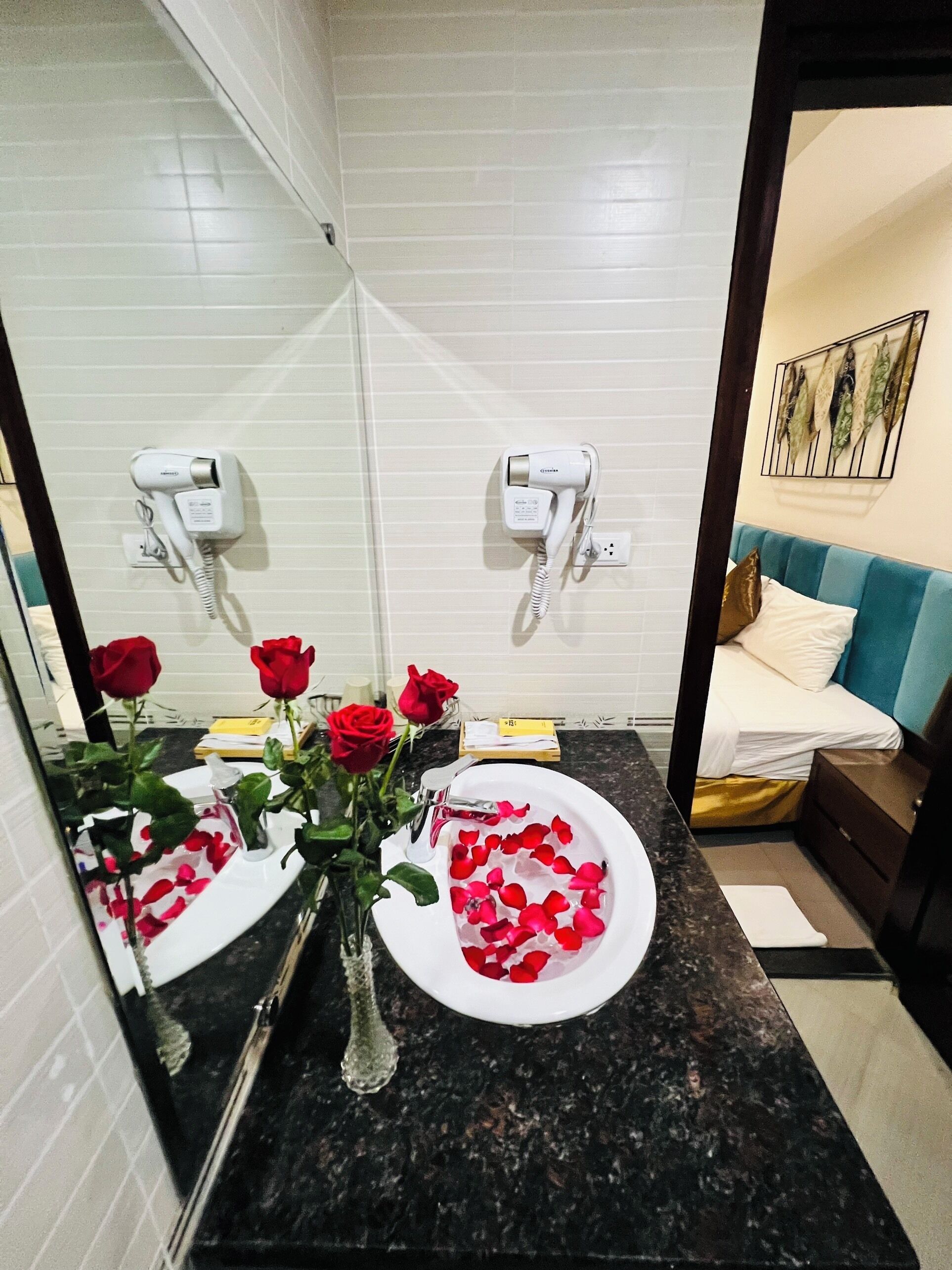 A bathroom with two sinks, a mirror, and a bed visible through an open door.