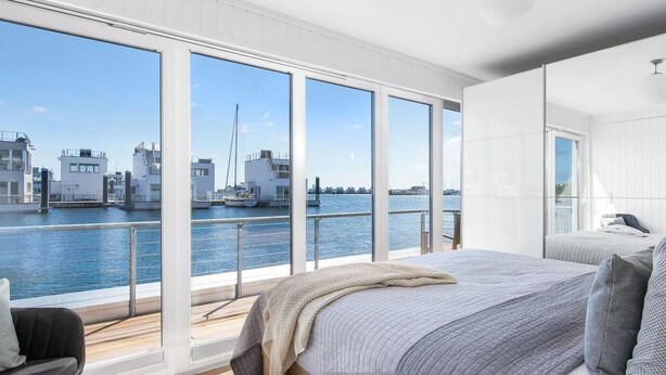 Une chambre moderne dotée de grandes fenêtres donnant sur un port de plaisance.