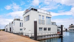Une propriété située au bord de l’eau, dotée d’un design moderne, comprenant une terrasse en bois et un canal.
