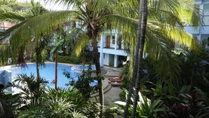 Ein Pool, umgeben von Palmen und ein Gebäude mit blauer Fassade.