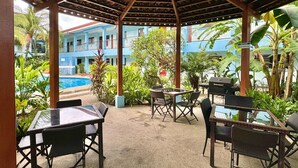 Ein überdachter Außenbereich mit Pool, Tischen, Stühlen und Grill.