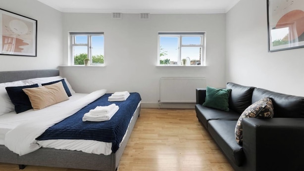 A modern bedroom with a bed, a sofa, two windows, and a radiator. - Crouch Hill N4, Crouch Hill, Finsbury Park (London)