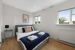 A modern bedroom with a bed, bedside table, and a window.