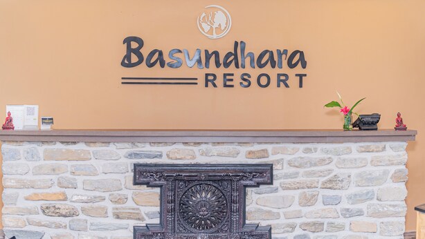 A reception desk with a stone wall and a sign that reads "Basundhara Resort". - Basundhara Resort Pokhara (Pokhara)
