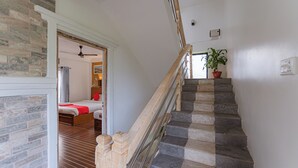 A staircase with stone steps and a wooden handrail, leading to a bedroom with a bed and a potted plant. - Basundhara Resort Pokhara (Pokhara)