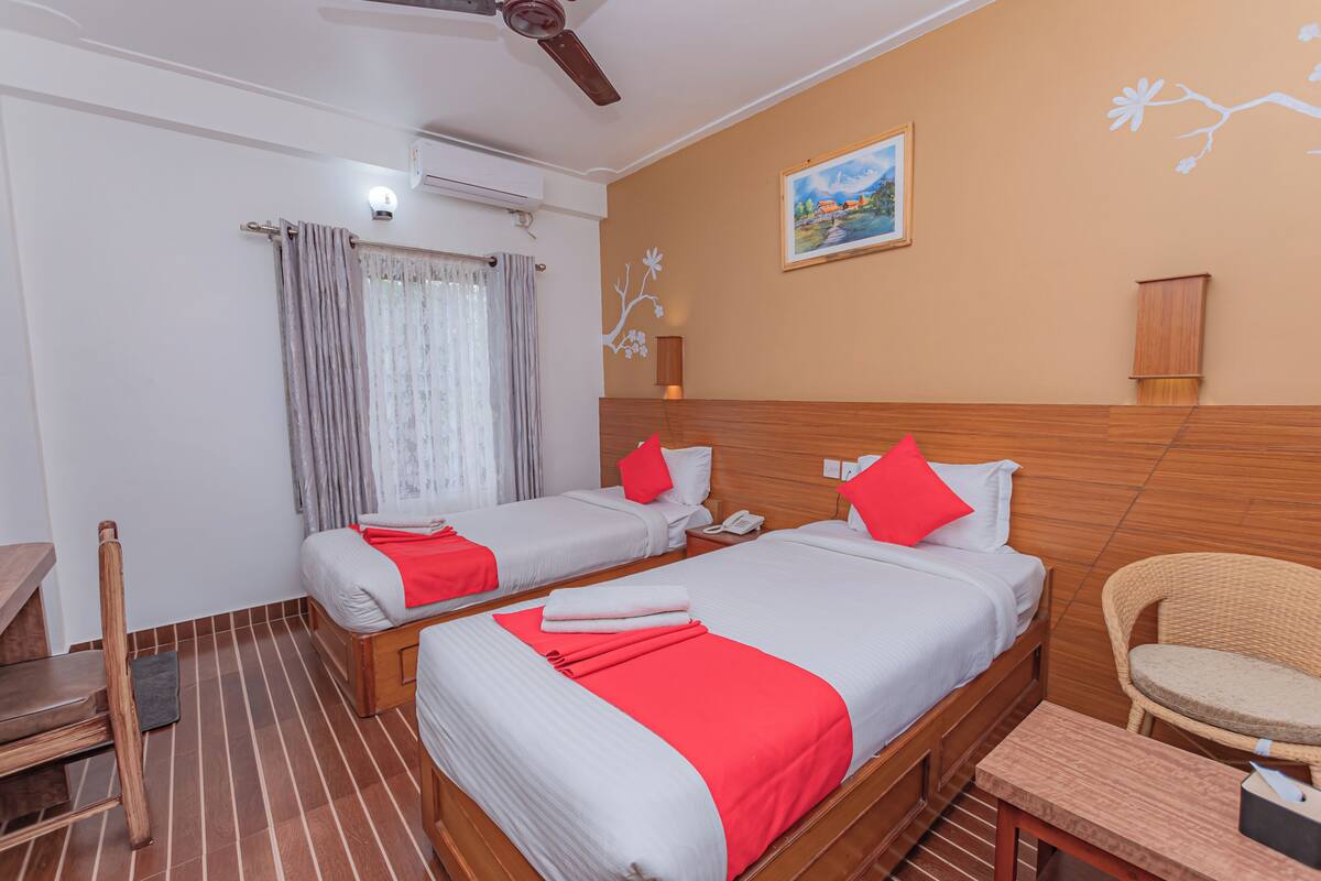 A hotel room with two beds, a wooden headboard, a chair, a desk, and a painting on the wall.