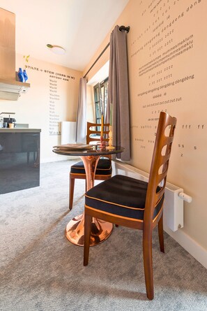 Cozy dining area with a round table and single chair, featuring classic design and a unique script-adorned wall.