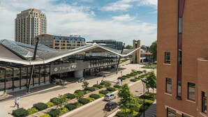 Un edificio moderno con una estructura de techo distintiva, una torre del reloj y un estacionamiento con vehículos.