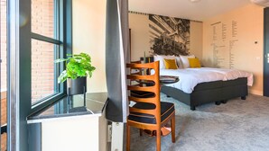 Un dormitorio moderno con cama, una silla, una mesita y una planta en maceta.