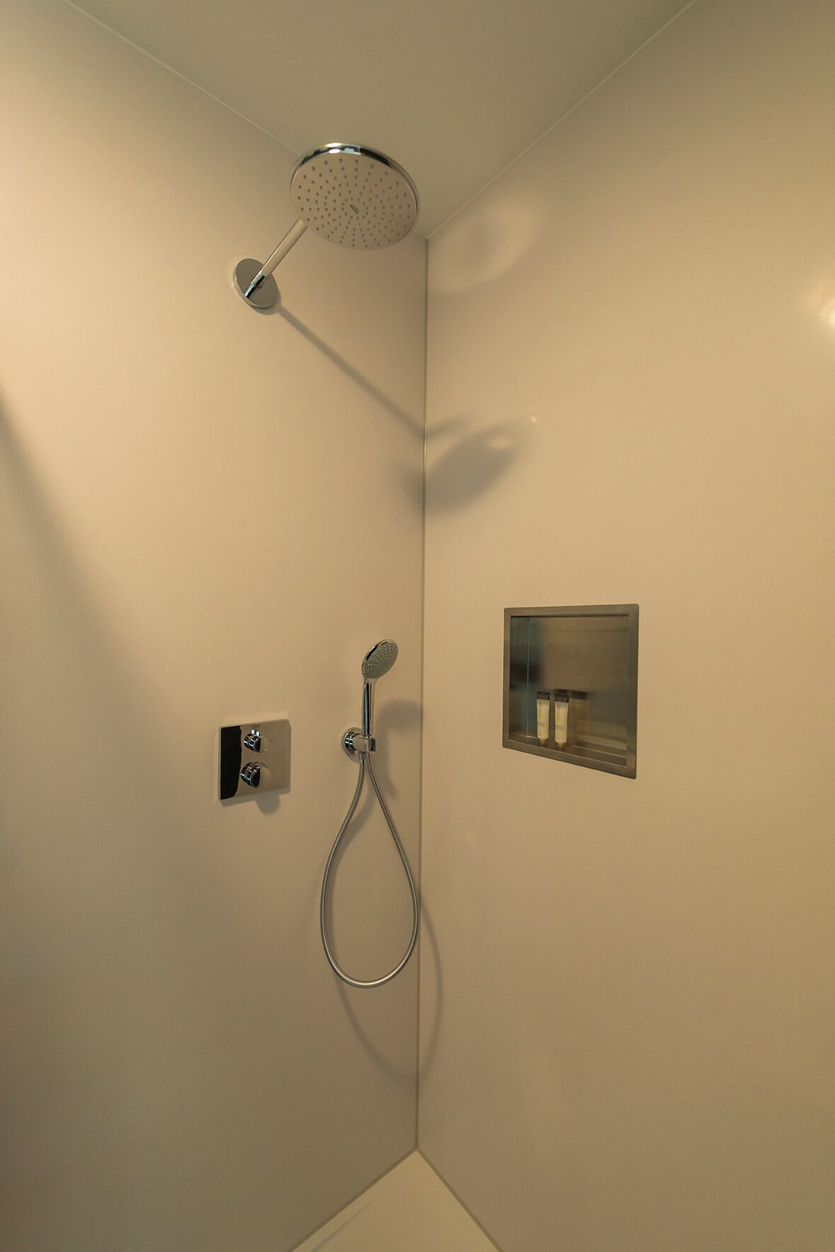 A modern shower with a handheld showerhead and a wall-mounted control panel.