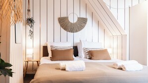 A bedroom with a bed, pillows, a bedside table, a lamp, and a wall-mounted decorative piece.