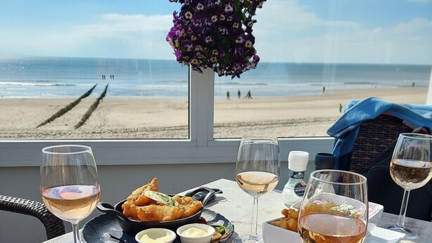 Une table avec des nachos, des verres à vin et une vue sur la plage.