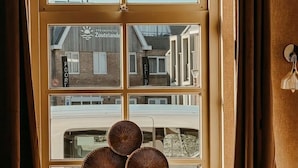 A window with a view of a building labeled 'STRANONOTEL Zouteland,' a window sill with three decorative items, and a curtain on the right.