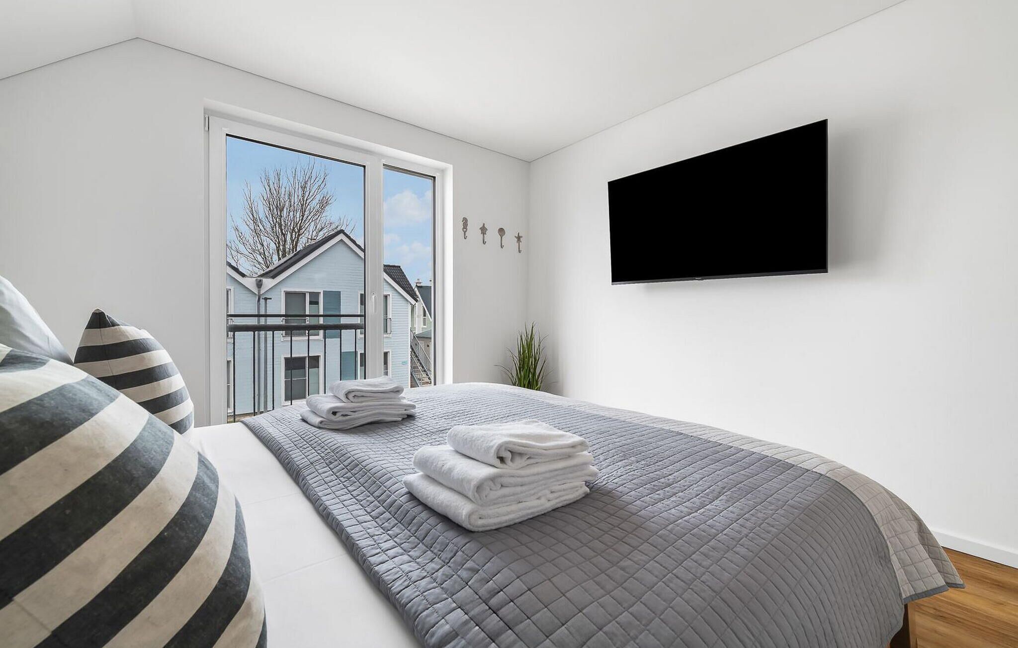 Une chambre à coucher avec un lit, une télévision et une vue sur une maison par la fenêtre.