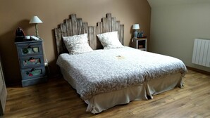 Une chambre à coucher avec une tête de lit en bois, un lit avec une literie à motifs, une table de chevet avec une lampe et une commode avec des horloges.
