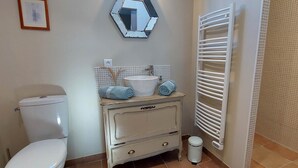 Une salle de bain comprenant des toilettes, un lavabo avec un miroir, un porte-serviettes et un radiateur.